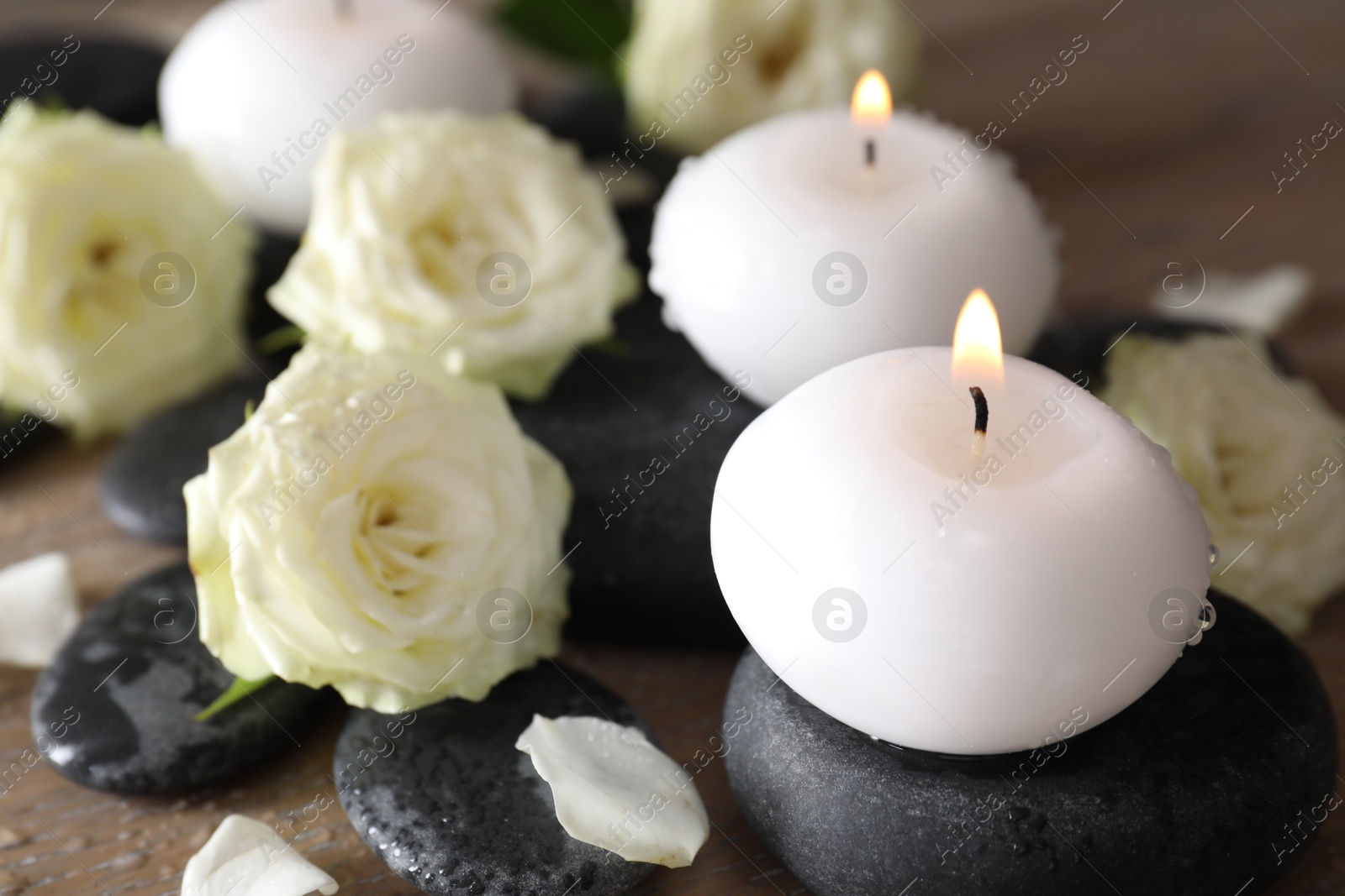 Burning candles, stones and rose flowers on wooden table, closeup Photo of Burning candles, stones and rose flowers on wooden table, closeup
