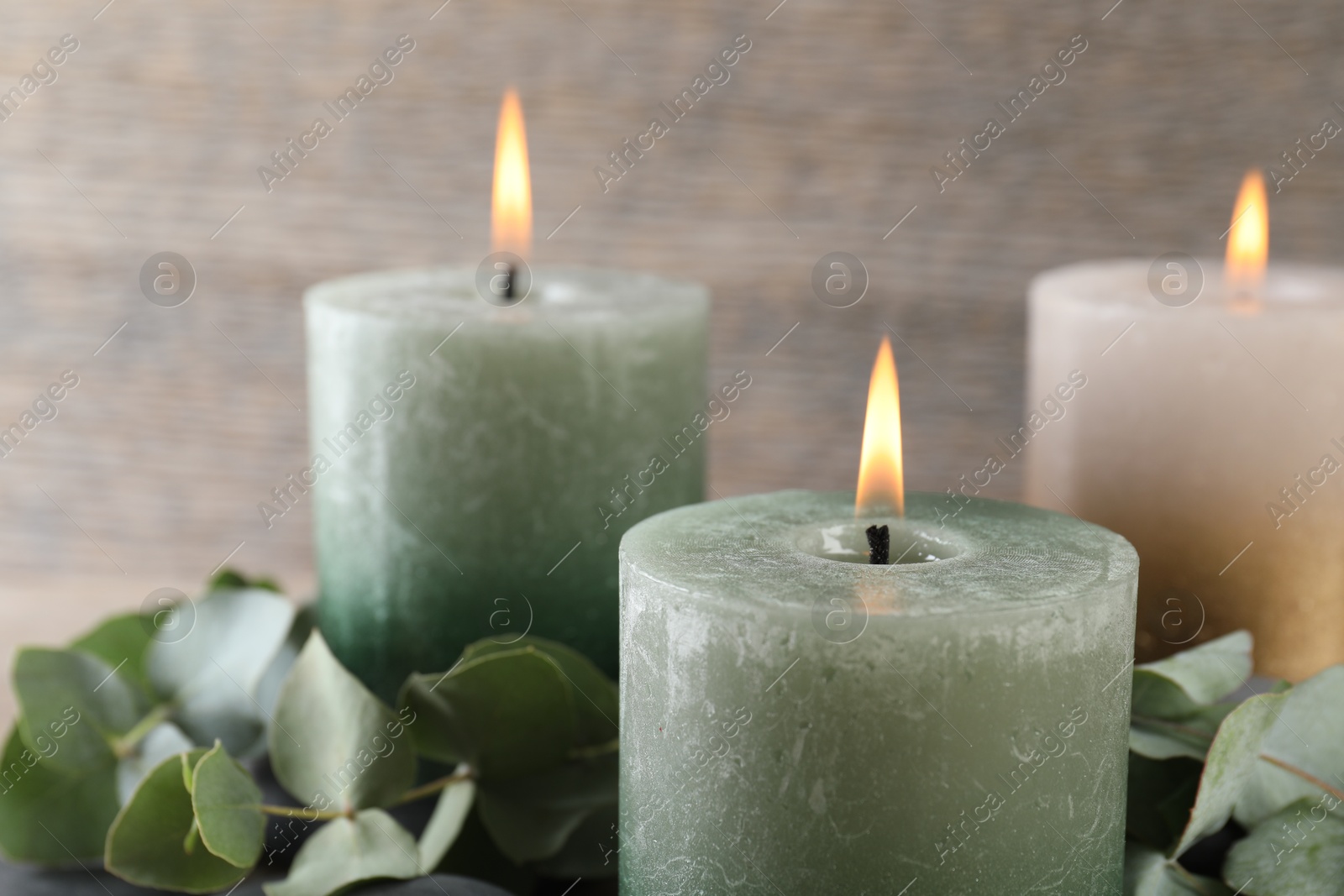Photo of Burning candles, stones and eucalyptus branches on table, closeup