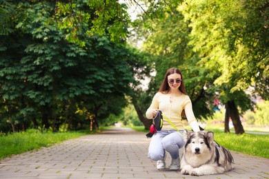 Photo of Happy woman with her cute Alaskan malamute dog in park. Space for text