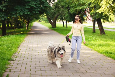 Photo of Happy woman with her cute Alaskan malamute dog in park. Space for text
