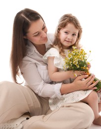 Photo of Mother and her little daughter with bouquet of beautiful chamomile flowers on white background