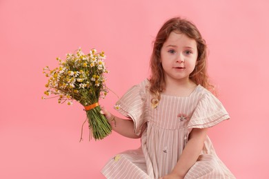 Photo of Cute little girl with bouquet of beautiful chamomile flowers on pink background