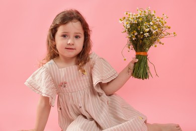 Photo of Cute little girl with bouquet of beautiful chamomile flowers on pink background