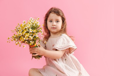 Photo of Cute little girl with bouquet of beautiful chamomile flowers on pink background