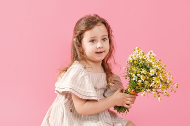 Photo of Cute little girl with bouquet of beautiful chamomile flowers on pink background