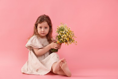 Photo of Cute little girl with bouquet of beautiful chamomile flowers on pink background, space for text