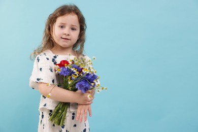 Photo of Cute little girl with bouquet of beautiful flowers on light blue background, space for text