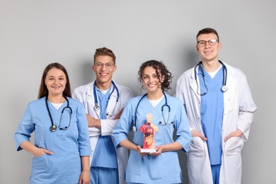 Photo of Group of medical students with human body model on light grey background