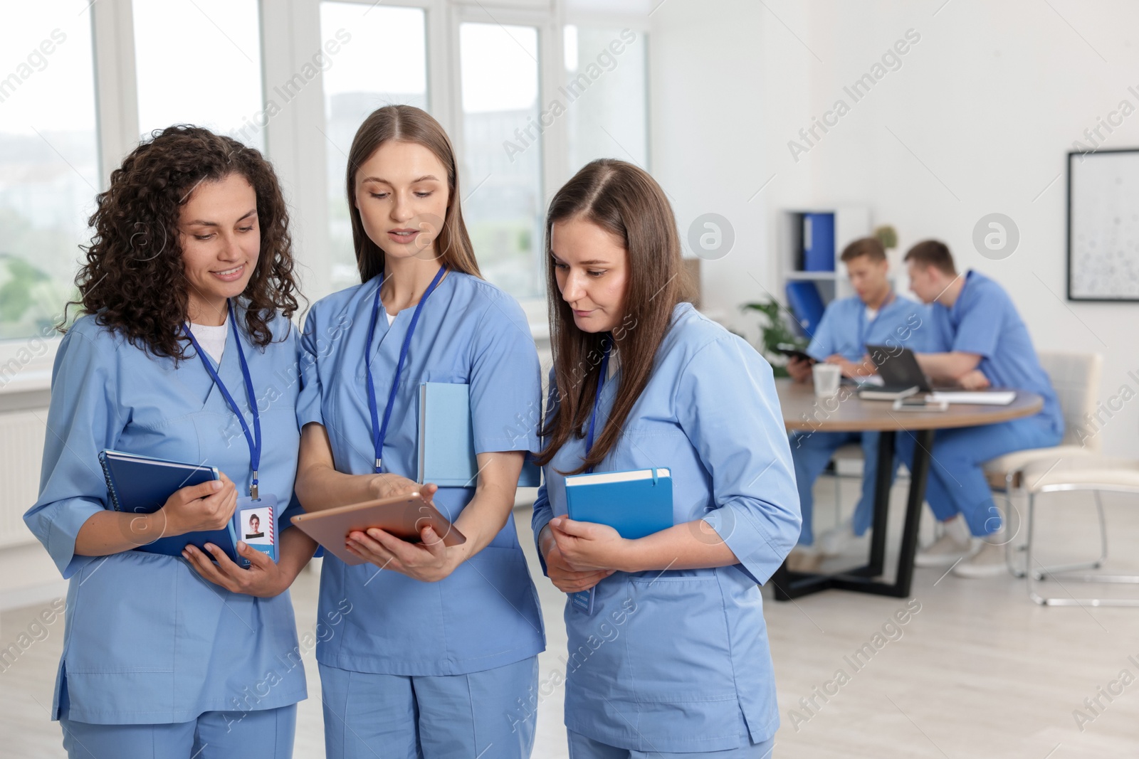 Photo of Medical students in uniforms studying together indoors, selective focus