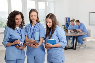 Photo of Medical students in uniforms studying together indoors, selective focus