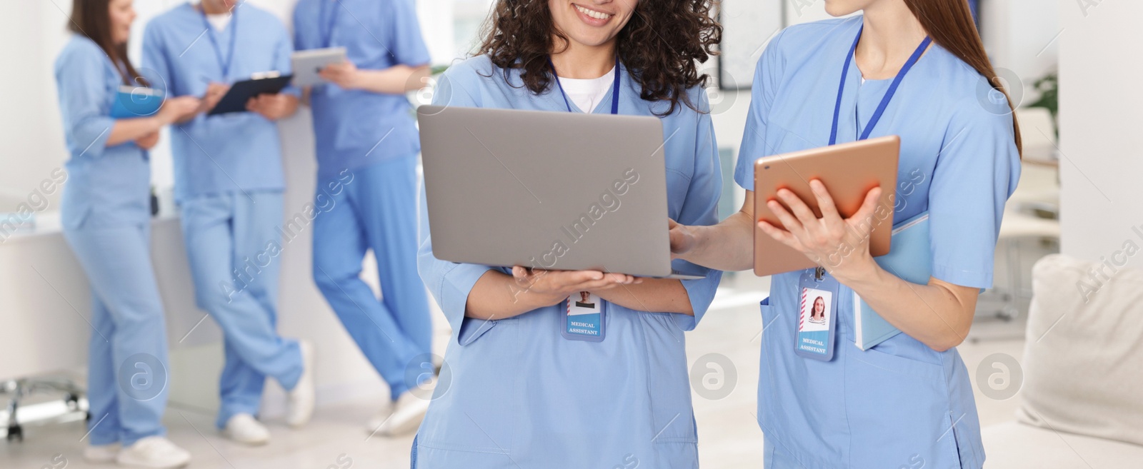 Medical students in uniforms with tablet and laptop indoors, selective focus Photo of Medical students in uniforms with tablet and laptop indoors, selective focus