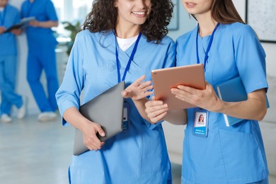 Photo of Medical students in uniforms with tablet and laptop indoors, selective focus