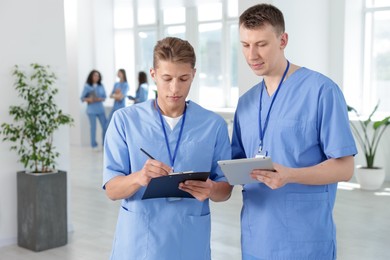 Photo of Medical students in uniforms studying together indoors, selective focus