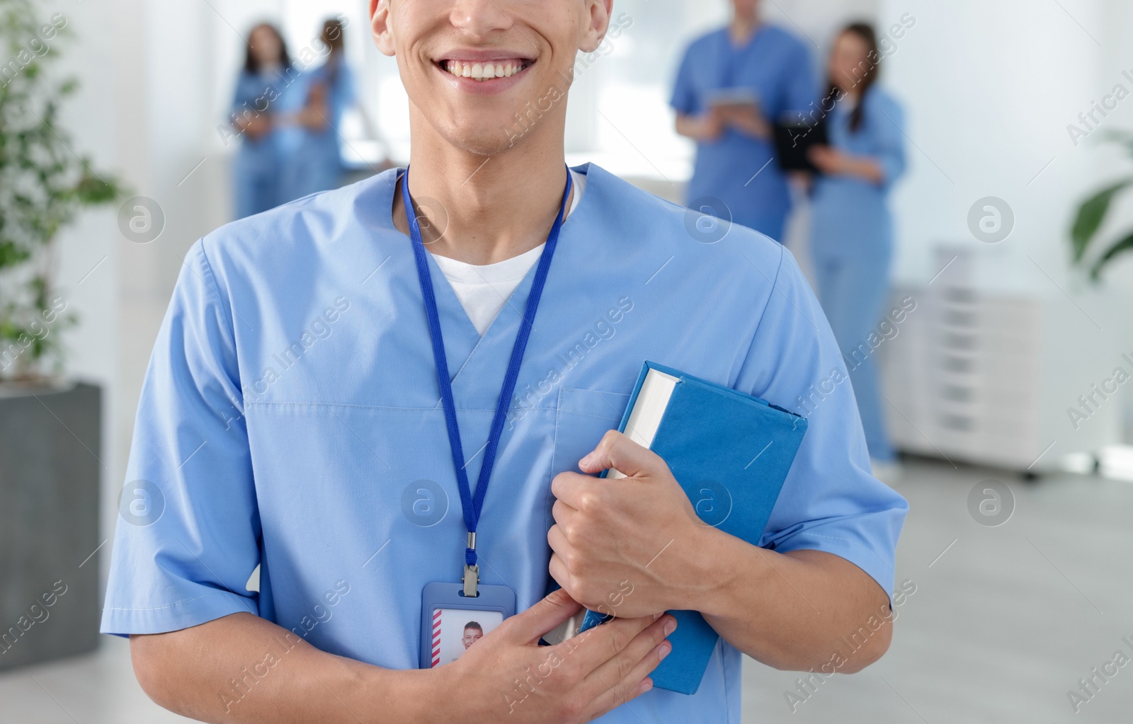Medical student in uniform with book indoors, selective focus Photo of Medical student in uniform with book indoors, selective focus
