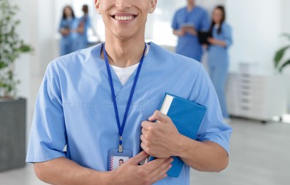 Photo of Medical student in uniform with book indoors, selective focus