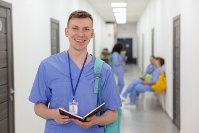 Photo of Medical student in uniform with backpack and notebook at university, selective focus