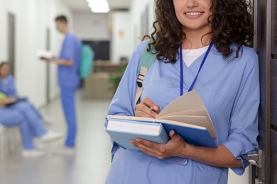 Photo of Medical student in uniform with books indoors, selective focus
