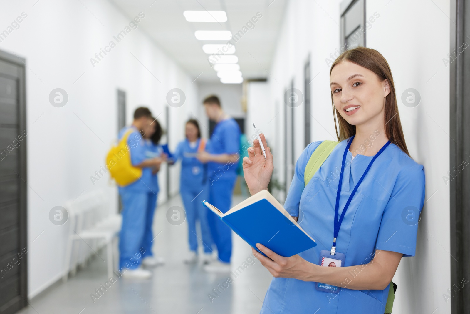 Medical student in uniform with backpack and notebook indoors, selective focus Photo of Medical student in uniform with backpack and notebook indoors, selective focus