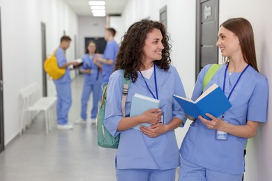 Photo of Medical students in uniforms studying together indoors, selective focus
