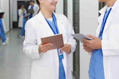 Photo of Medical students in uniforms with tablets indoors, selective focus