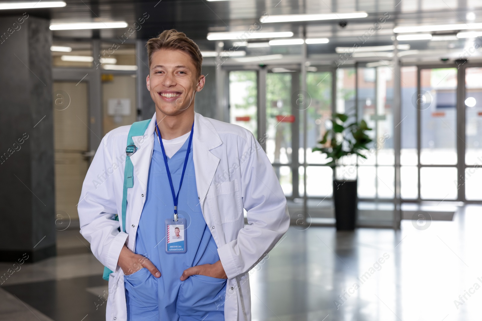 Medical student in uniform with backpack indoors, space for text Photo of Medical student in uniform with backpack indoors, space for text