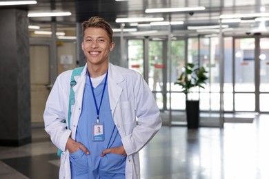 Photo of Medical student in uniform with backpack indoors, space for text