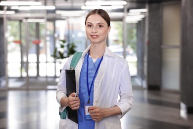 Photo of Medical student in uniform with backpack and clipboard indoors