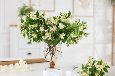 Photo of Bouquet of beautiful jasmine flowers in vase on white table indoors