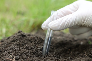 Photo of Scientist taking soil sample for research outdoors, closeup. Space for text