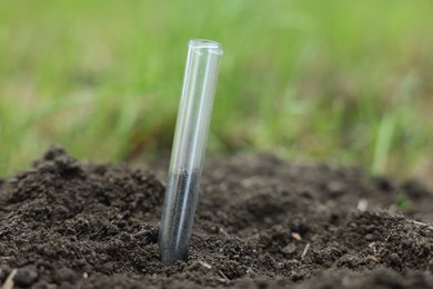 Photo of Test tube with soil sample outdoors, closeup. Space for text