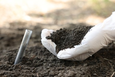 Photo of Scientist taking soil sample for research outdoors, closeup