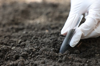 Photo of Scientist taking soil sample for research outdoors, closeup. Space for text