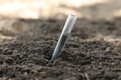 Photo of Test tube with soil sample outdoors, closeup. Space for text