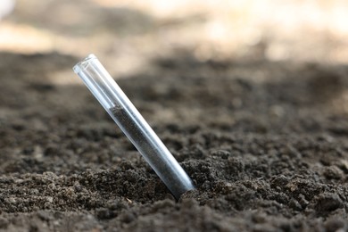 Photo of Test tube with soil sample outdoors, closeup. Space for text