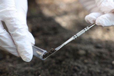 Photo of Scientist taking soil sample for research outdoors, closeup