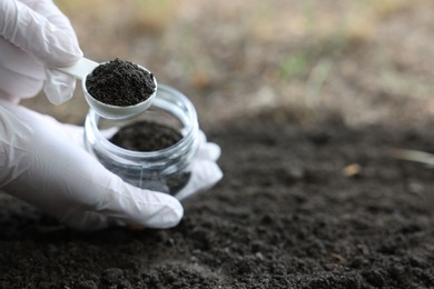 Photo of Scientist taking soil sample for research outdoors, closeup. Space for text