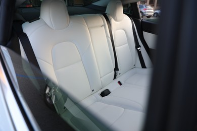 Photo of Modern car interior with seats and safety belts, view from outside