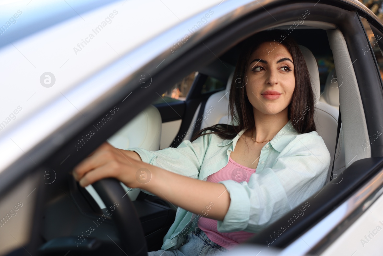 Woman holding steering wheel while driving car, view from outside Photo of Woman holding steering wheel while driving car, view from outside
