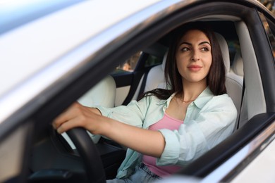 Photo of Woman holding steering wheel while driving car, view from outside