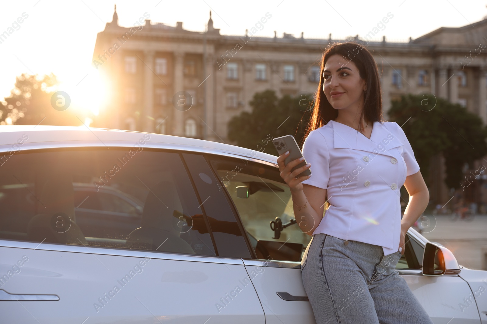 Beautiful woman with smartphone near modern car outdoors on sunny day Photo of Beautiful woman with smartphone near modern car outdoors on sunny day