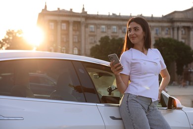 Photo of Beautiful woman with smartphone near modern car outdoors on sunny day