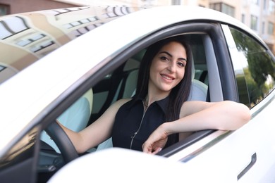 Photo of Woman behind steering wheel of modern car, view from outside