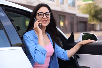 Photo of Woman talking on smartphone while getting out of car outdoors