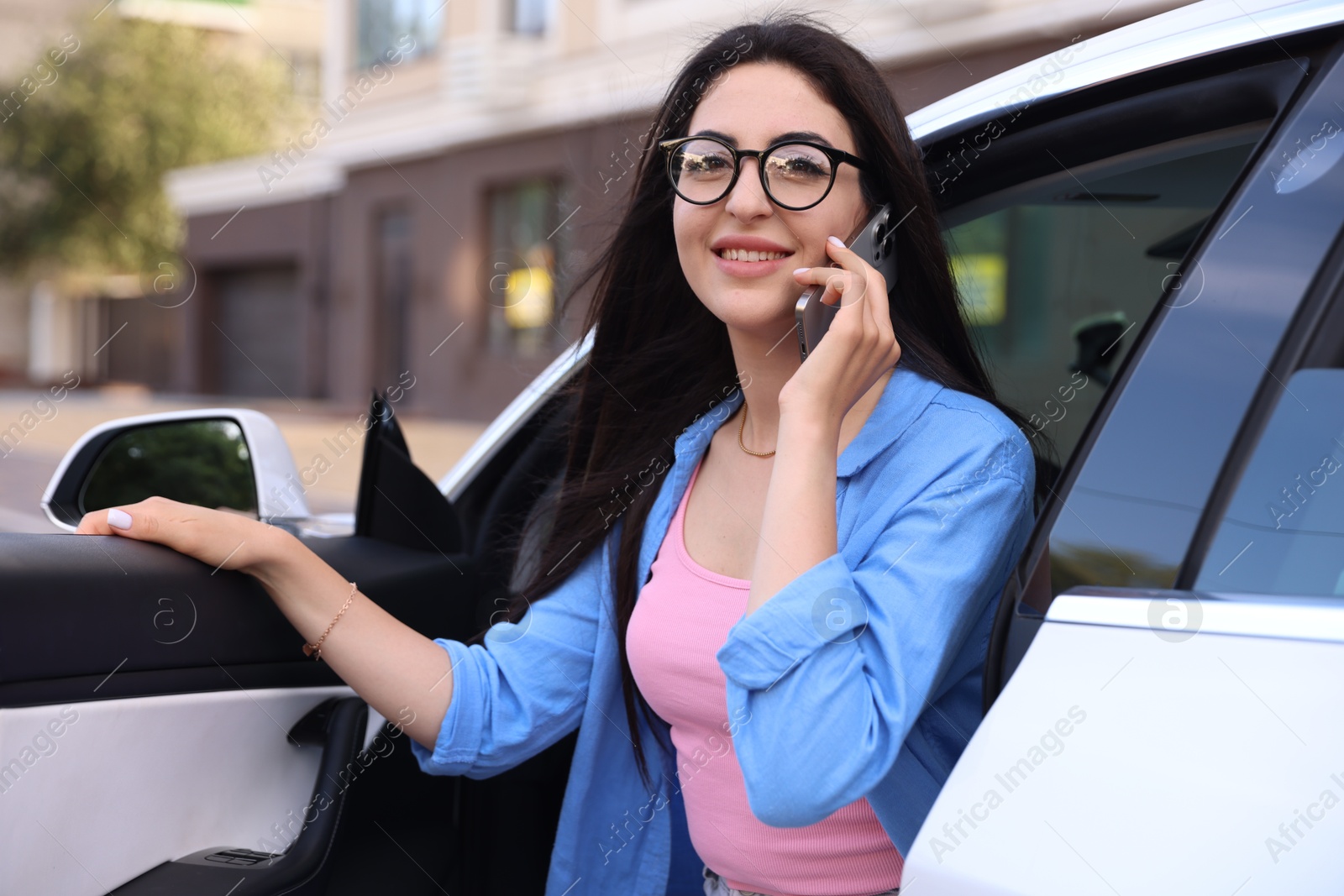 Woman talking on smartphone while getting out of car outdoors Photo of Woman talking on smartphone while getting out of car outdoors