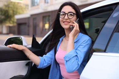 Photo of Woman talking on smartphone while getting out of car outdoors