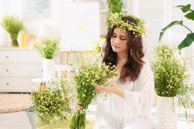 Photo of Portrait of beautiful woman with chamomile flowers indoors