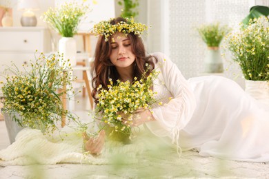 Photo of Beautiful woman with chamomile flowers on floor indoors