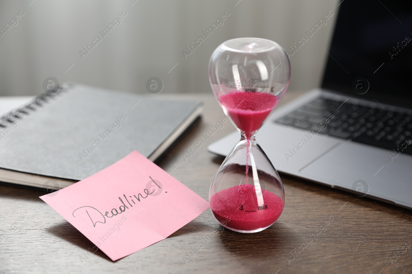 Sticky note with word Deadline, hourglass, notebook and laptop on wooden table indoors, closeup Photo of Sticky note with word Deadline, hourglass, notebook and laptop on wooden table indoors, closeup
