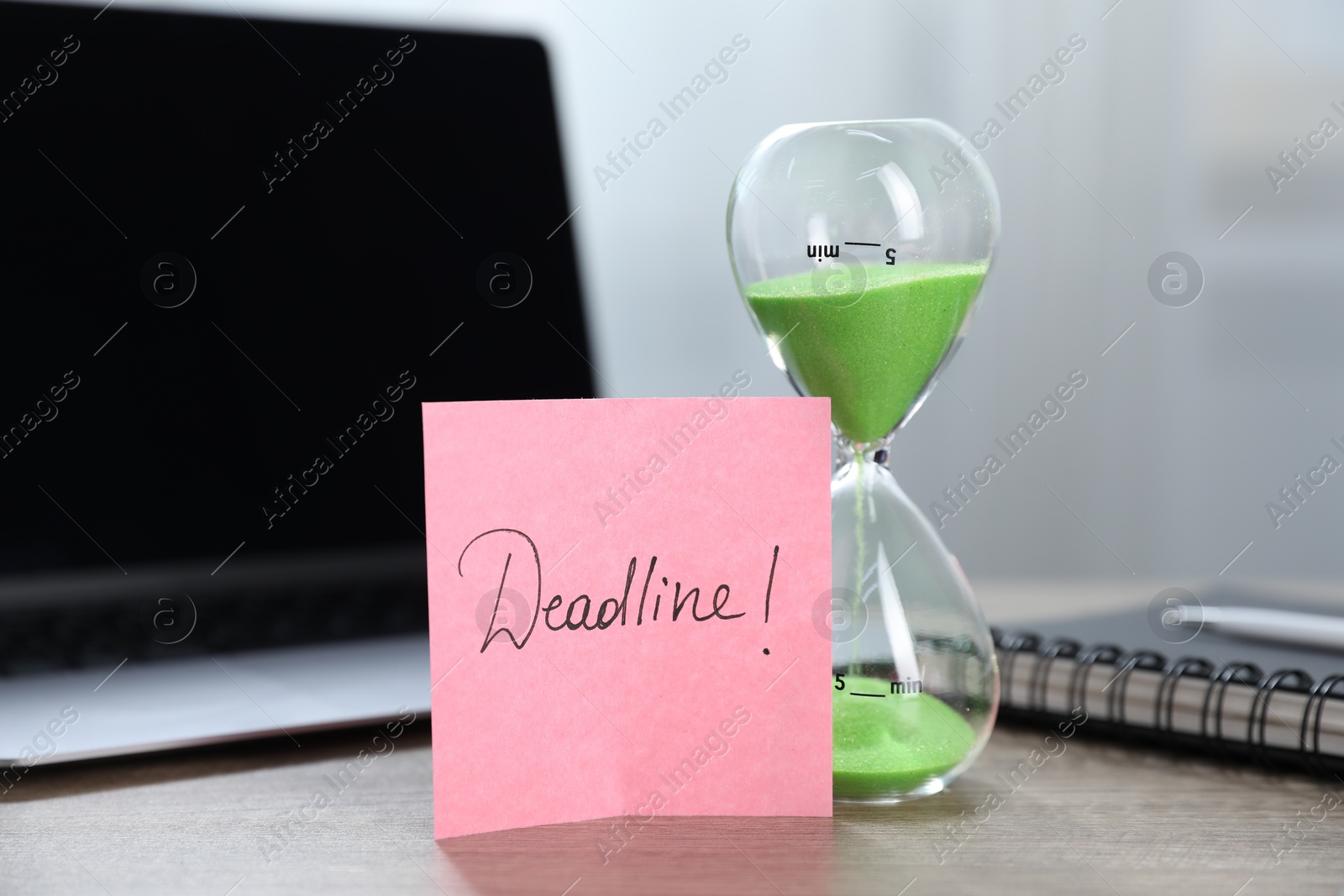Sticky note with word Deadline, hourglass, notebook and laptop on wooden table indoors, closeup Photo of Sticky note with word Deadline, hourglass, notebook and laptop on wooden table indoors, closeup