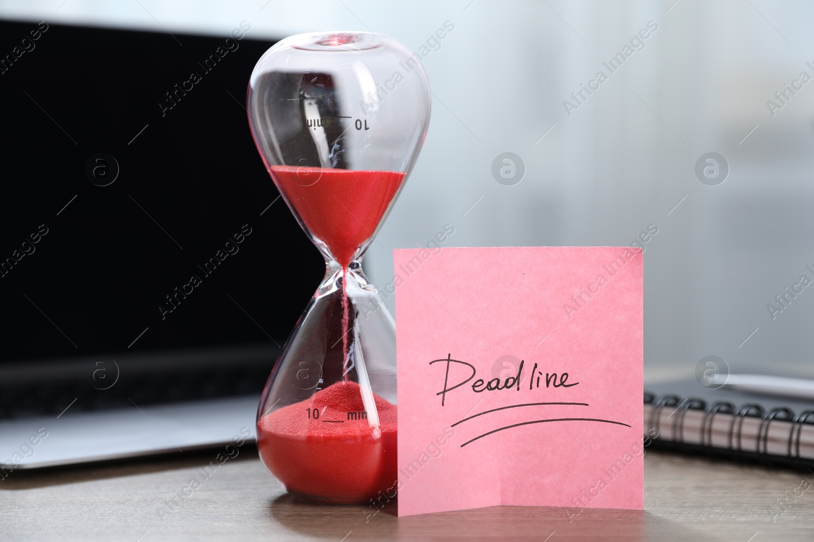 Sticky note with word Deadline, hourglass, notebook and laptop on wooden table indoors, closeup Photo of Sticky note with word Deadline, hourglass, notebook and laptop on wooden table indoors, closeup